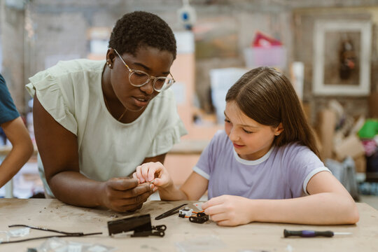 Female teacher helping student working on robotics project in technology class at school