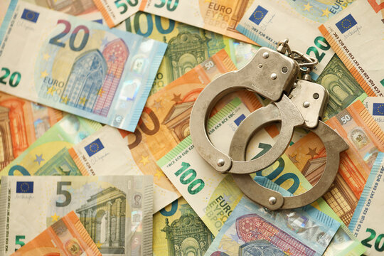 Many European euro money bills and handcuffs. Lot of banknotes of European union currency and cuffs close up