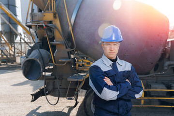 Portrait young man driver of concrete mixer truck with hard hat on cement factory
