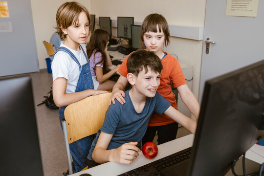 Male and female students with down syndrome girl using computer at desk in classroom