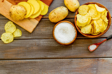 Homemade low calorie potato chips with raw potatoes on board, top view
