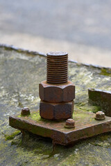 An old rusted bolt and nut hold together a metal structure.