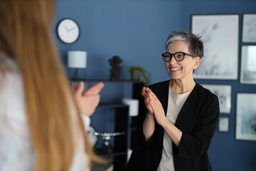 In a successful interview, a businesswoman claps, showcasing teamwork and corporate achievement in the office.