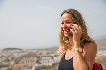 A caucasian woman is talking on her cell phone while smiling
