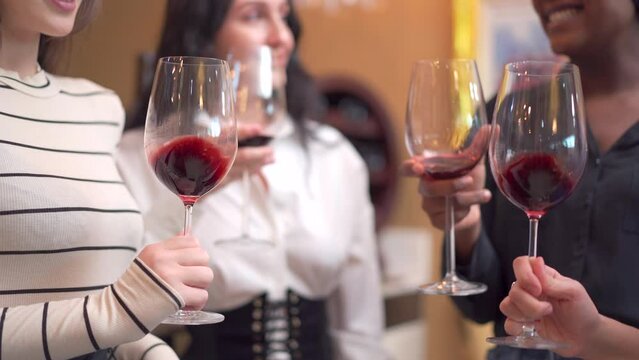 Group of diverse ethnicity people enjoy testing red wine together.