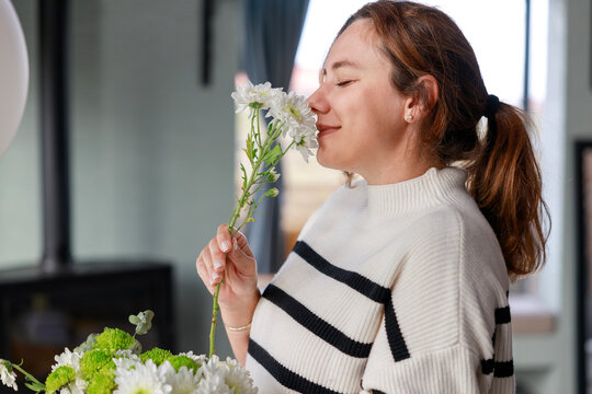 Young beautiful woman enjoying the smell of fresh flowers