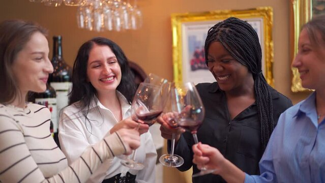 Group of diverse ethnicity people enjoy testing red wine together.