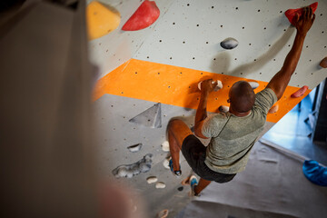 Close Up Of Determined Man Tackling Climbing Wall At Indoor Activity Centre