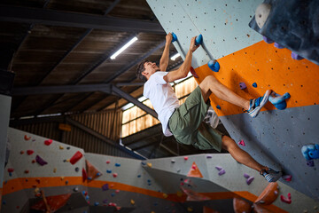 Close Up Of Determined Man Tackling Climbing Wall At Indoor Activity Centre