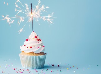 Festive cupcake with sparkler and sprinkles on a bright blue background - perfect for a birthday or special occasion - obrazy, fototapety, plakaty