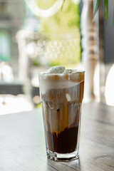 Iced coffee with whipped cream in a glass on a wooden table