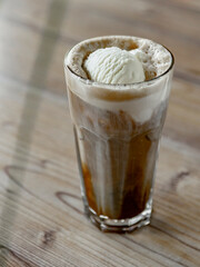 Iced coffee with whipped cream in a glass on a wooden table
