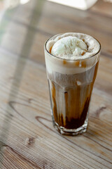 Iced coffee with whipped cream in a glass on a wooden table