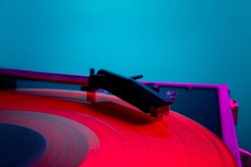 Vinyl record player, bright lights disco-bokeh. Needle on vinyl record in bright pink neon light...