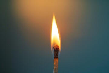 Detailed close-up of a single match with a burning flame on a blurred blue background.