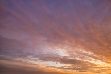 A beautiful sky tinted by the sun leaving vibrant shades of gold, pink, blue and multicolored. Clouds in the twilight evening and morning sky. Cloudy sky background in the evening and during the day.