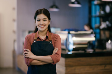 A woman wearing a blue apron and a red shirt is smiling for the camera