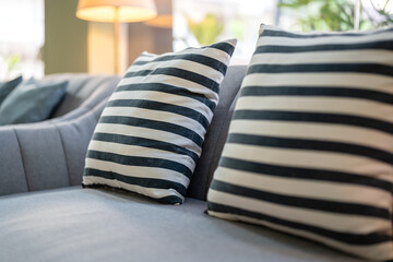 Naklejka premium A couple of black-white pillows on the grey sofa seat. Interior furniture decoration object, close-up.