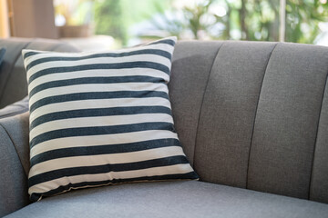 Fototapeta premium A couple of black-white pillows on the grey sofa seat. Interior furniture decoration object, close-up.