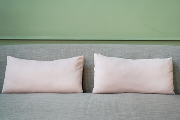 Square white pillow placed on grey sofa at the hotel lobby room. Interior decoration and furniture...