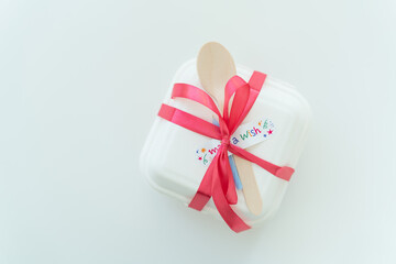 White gift box with red ribbon, wooden spoons, and make a wish text on a white background.