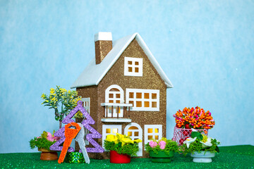 Brown house with keys on a Christmas tree and many flowers around on a blue background
