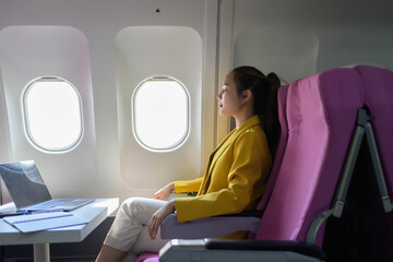 A woman is sitting in a pink chair on an airplane