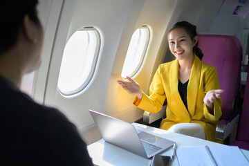 A woman in a yellow jacket is talking to a man on a laptop