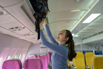 A woman is reaching for her backpack on an airplane
