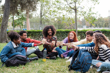 Group of young people meeting outdoors in the park toasting with recyclable glasses. Concept:...