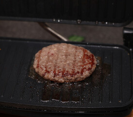 Delicious hamburger patties cooking on electric grill, closeup