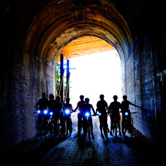 Group of People Biking Through Tunnel with Headlights Hiawatha Trail