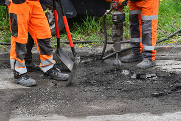 Professional Workers are repairing the asphalt road with jackhammer. Repair work on the trafic road.