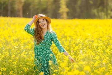 Foto op Canvas Beautiful woman walking in the field at sunny summer day. Nature, vacation, relax and lifestyle. View scenic landscape yellow flower blooming. © maxbelchenko