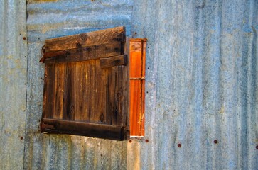weathered wooden window blind on an old abandoned metal hut