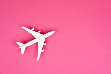 Top view composition of miniature commercial airplane isolated on fuchsia background. Summer...