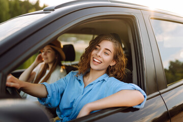 Beautiful female friends in the car enjoy a car trip together. Lifestyle, travel, tourism, nature, active life.