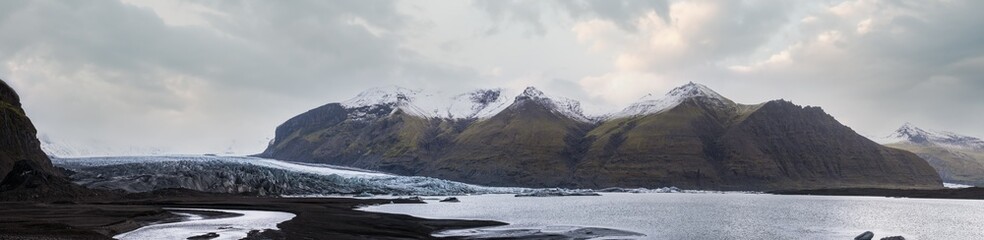 Fototapeta na wymiar Skaftafellsjökull glacier, Iceland. Glacier tongue slides from the Vatnajökull icecap or Vatna Glacier near subglacial Esjufjöll volcano. Glacial lagoon with ice blocks and surrounding mountains.