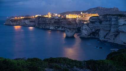 Die Beleuchtung von Bonifacio spiegelt sich im Meer, Bonifacio zur blauen Stunde