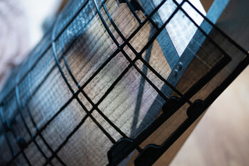 A black and white photo of a window screen with a blue background. The photo has a moody and...