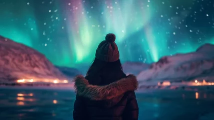 Store enrouleur Aurores boréales A person stands in snow field with beautiful aurora northern lights in night sky in winter.