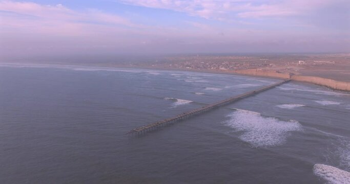 Shot of dock at sunset, with the seafront behind. Aerial shot of the Puerto Eten beach sea at sunset.