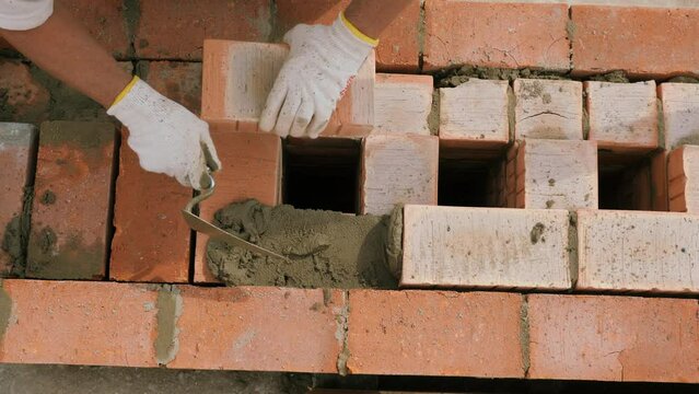 Laying out a brick chimney chimney of a private wooden house. Construction work of a bricklayer. Refractory mortar and red brick. High-altitude work.