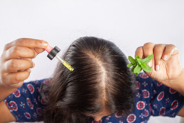 Fototapeta premium female using Peppermint herb essential oil for the treatment of female pattern baldness or alopecia