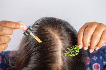 indian women using rosemary essential hair oil to prevent hair fall, closeup view