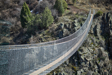 Excursion suspension bridge over the gorge. Sightseeing holiday tour, Kyrgyzstan. Crossing between...
