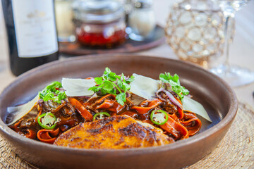 Pasta fresca hecha en casa teñida con puré de mix de chiles secos , con birria típica de Jalisco, acompañada de quesabirria, cebolla caramelizada, cilantro, chile serrano y queso nacional añejado