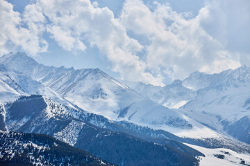 Fototapeta na wymiar Panoramic view snow capped high mountains. Chunkurchak valley in Kyrgyzstan. Winter natural landscape, mountain range wallpaper. Epic blue sky with white beautiful clouds