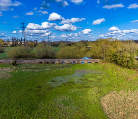An aerial view across meadows towards the packhorse bridge beside the Grand Union Canal in Aylestone Meadows, Leicester, UK in Springtime