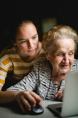 A girl teaches her grandmother how to use the computer. - 776202498